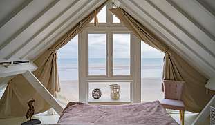 Helles Schlafzimmer unter dem Dach mit Fenster am Strand und direktem Meerblick