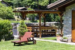 Gepflegter Garten mit Sonnenliege, überdachter Holzsitzgruppe und Natursteinmauer – ideal zum Entspannen am Ferienhaus bei Arco am Gardasee I WUNDERORTE